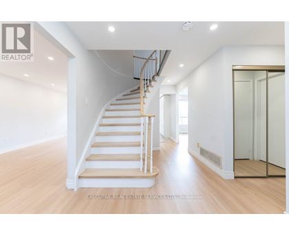 A spacious room with a wooden staircase and white walls.