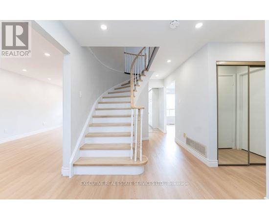 A spacious room with a wooden staircase and white walls.