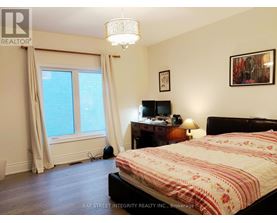 A bedroom with a bed, desk, and window.