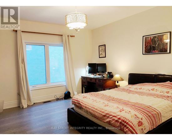 A bedroom with a bed, desk, and window.