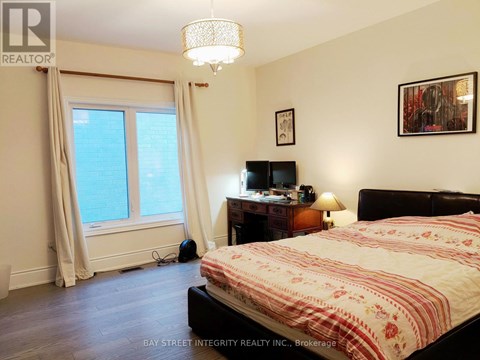 A bedroom with a bed, desk, and window.