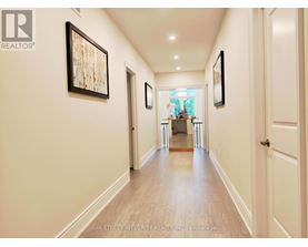 A hallway with a wooden floor and white walls, with a painting hanging on the wall.