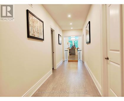 A hallway with a wooden floor and white walls, with a painting hanging on the wall.