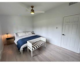 A bedroom with a bed, a bench, and a ceiling fan.