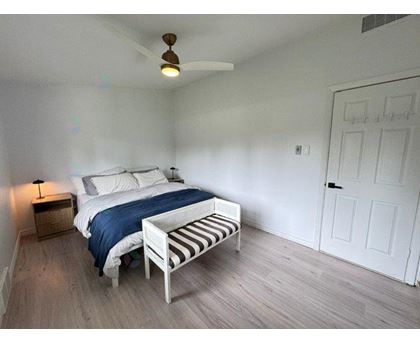A bedroom with a bed, a bench, and a ceiling fan.