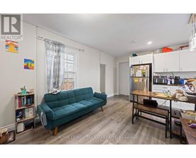 A living room with a green couch and a kitchen area in the background.