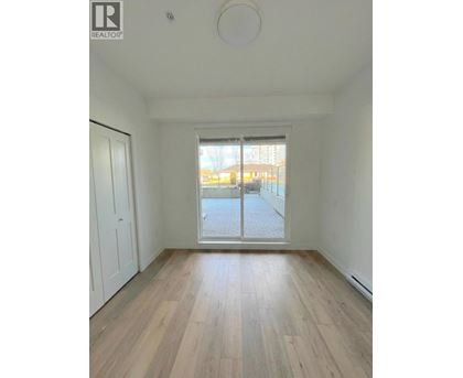 A room with wooden flooring and a sliding glass door leading to a balcony.