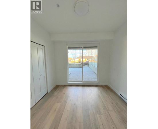 A room with wooden flooring and a sliding glass door leading to a balcony.