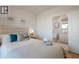 A bedroom with a large bed and a nightstand with a lamp.