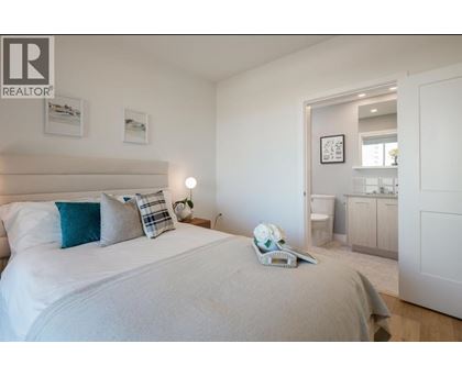 A bedroom with a large bed and a nightstand with a lamp.