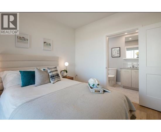 A bedroom with a large bed and a nightstand with a lamp.