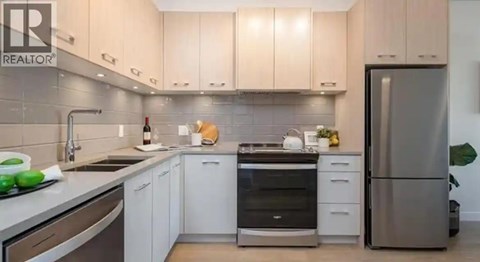 A modern kitchen with white cabinets and stainless steel appliances.
