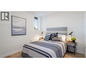A bedroom with a bed, a nightstand, and a painting on the wall.