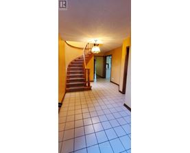 A hallway with a staircase and a chandelier.