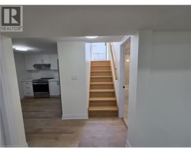 A staircase leads up to a window in a white room.
