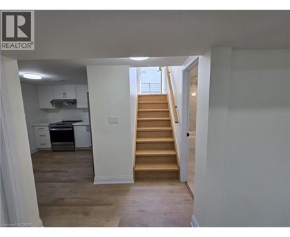 A staircase leads up to a window in a white room.