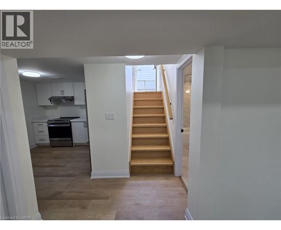 A staircase leads up to a window in a white room.