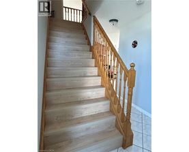 A wooden staircase with a white wall and a brown railing.