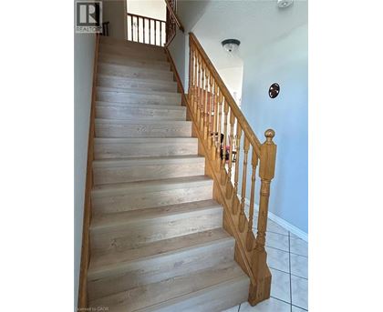 A wooden staircase with a white wall and a brown railing.