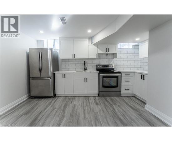 A kitchen with a refrigerator, oven, and cabinets.