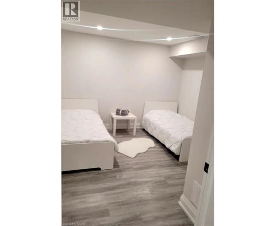 A bedroom with two beds and a nightstand.