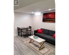 A living room with a grey couch, a white coffee table, and a painting on the wall.