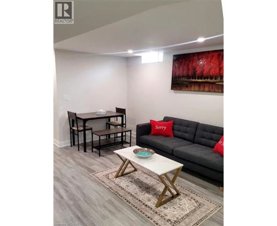 A living room with a grey couch, a white coffee table, and a painting on the wall.