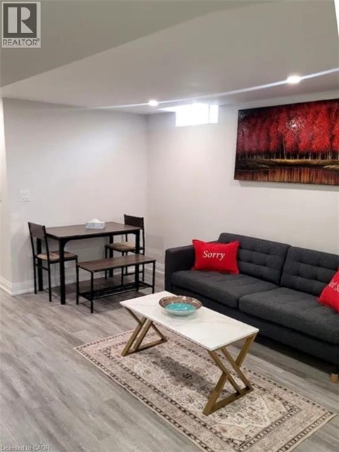 A living room with a grey couch, a white coffee table, and a painting on the wall.