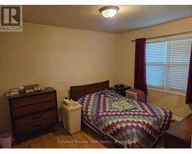 A bedroom with a bed, nightstand, and window with blinds.