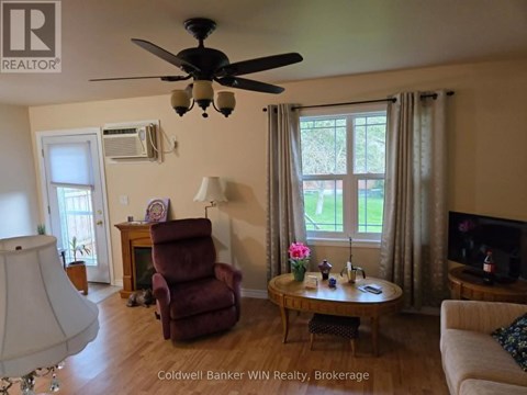 A living room with a red chair and a ceiling fan.