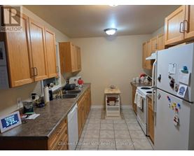 A kitchen with a refrigerator on the right and a sink in the middle.