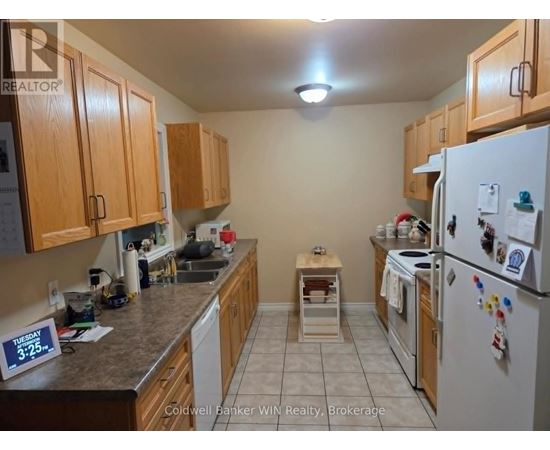 A kitchen with a refrigerator on the right and a sink in the middle.