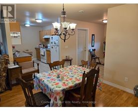 A dining room with a floral tablecloth and wooden chairs.