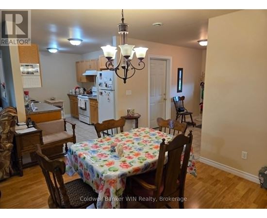 A dining room with a floral tablecloth and wooden chairs.