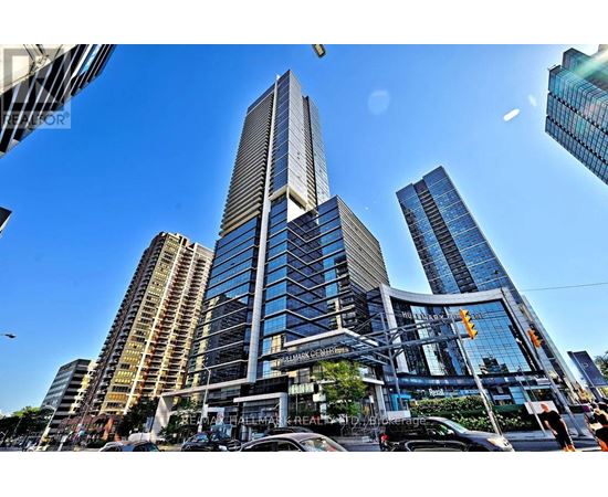 A tall building with a glass facade stands in the middle of a bustling city street.