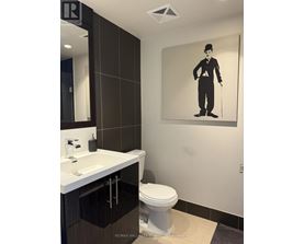A bathroom with a toilet, sink, and a picture of a man with a cane.