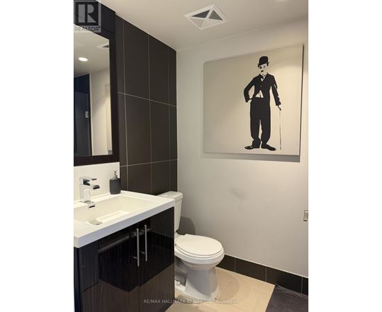 A bathroom with a toilet, sink, and a picture of a man with a cane.