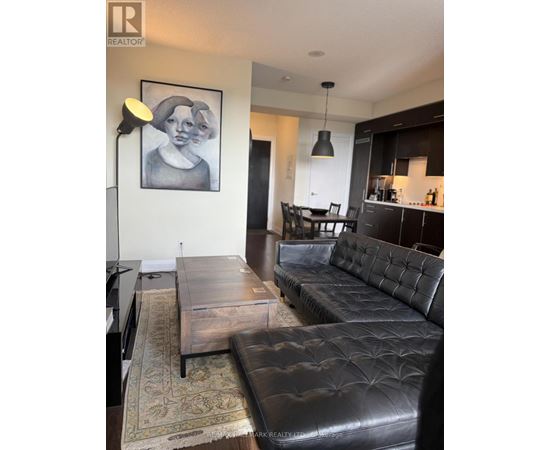 A living room with a black leather couch and a coffee table.