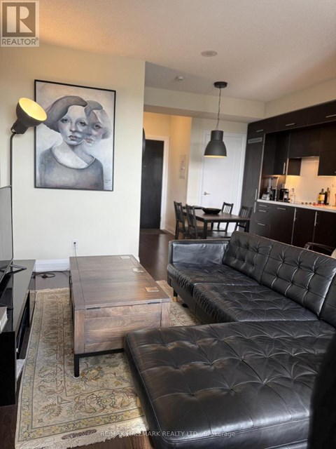 A living room with a black leather couch and a coffee table.