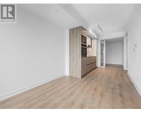 A spacious room with wooden flooring and a built-in cabinet.