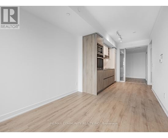 A spacious room with wooden flooring and a built-in cabinet.