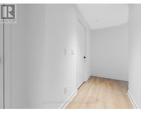 A white room with a wooden floor and a door on the left.