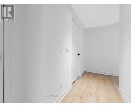 A white room with a wooden floor and a door on the left.