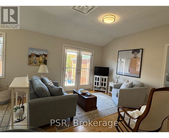 A living room with a grey couch and a painting of a woman on the wall.