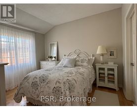 A bedroom with a bed, nightstand, and window with curtains.