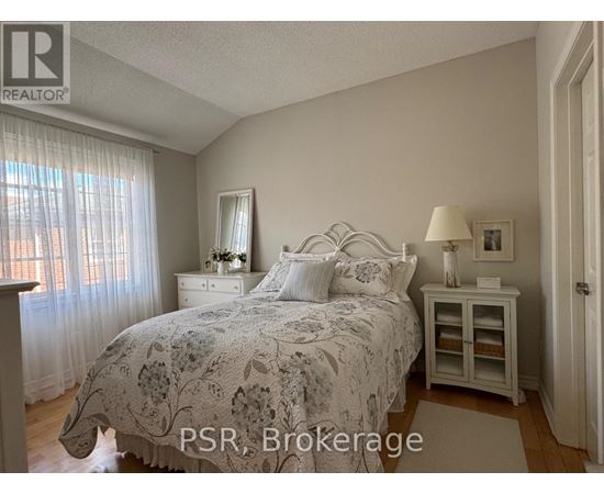 A bedroom with a bed, nightstand, and window with curtains.