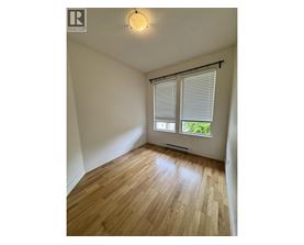 A room with wooden flooring and a window with blinds.
