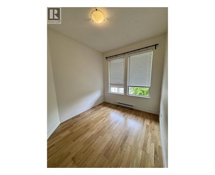 A room with wooden flooring and a window with blinds.