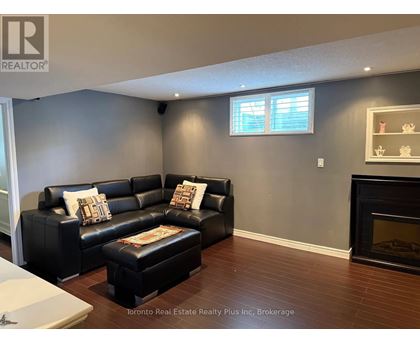 A living room with a black leather couch and ottoman.