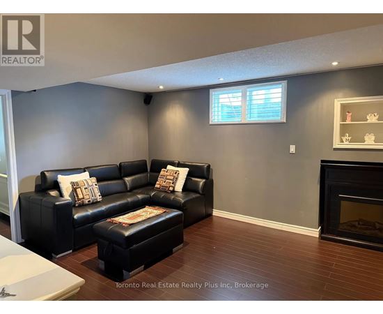 A living room with a black leather couch and ottoman.